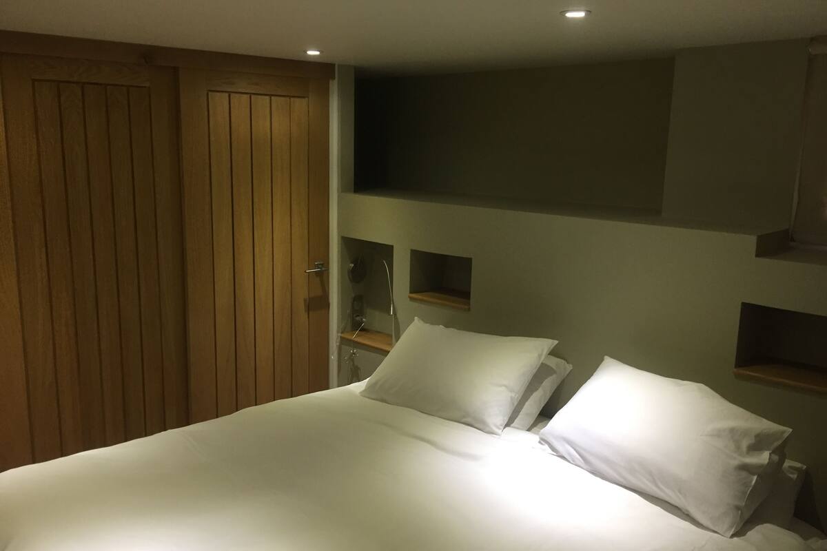 Un dormitorio con una cama grande, armario de madera y estanterías empotradas.