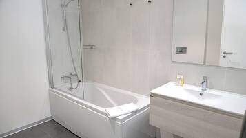 Ein modernes Badezimmer mit einer Duschkabine, einer weißen Badewanne und einem Waschtisch mit Waschbecken und Spiegel.