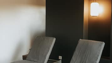 Two single beds with white frames and grey bedding, set against a dark accent wall.