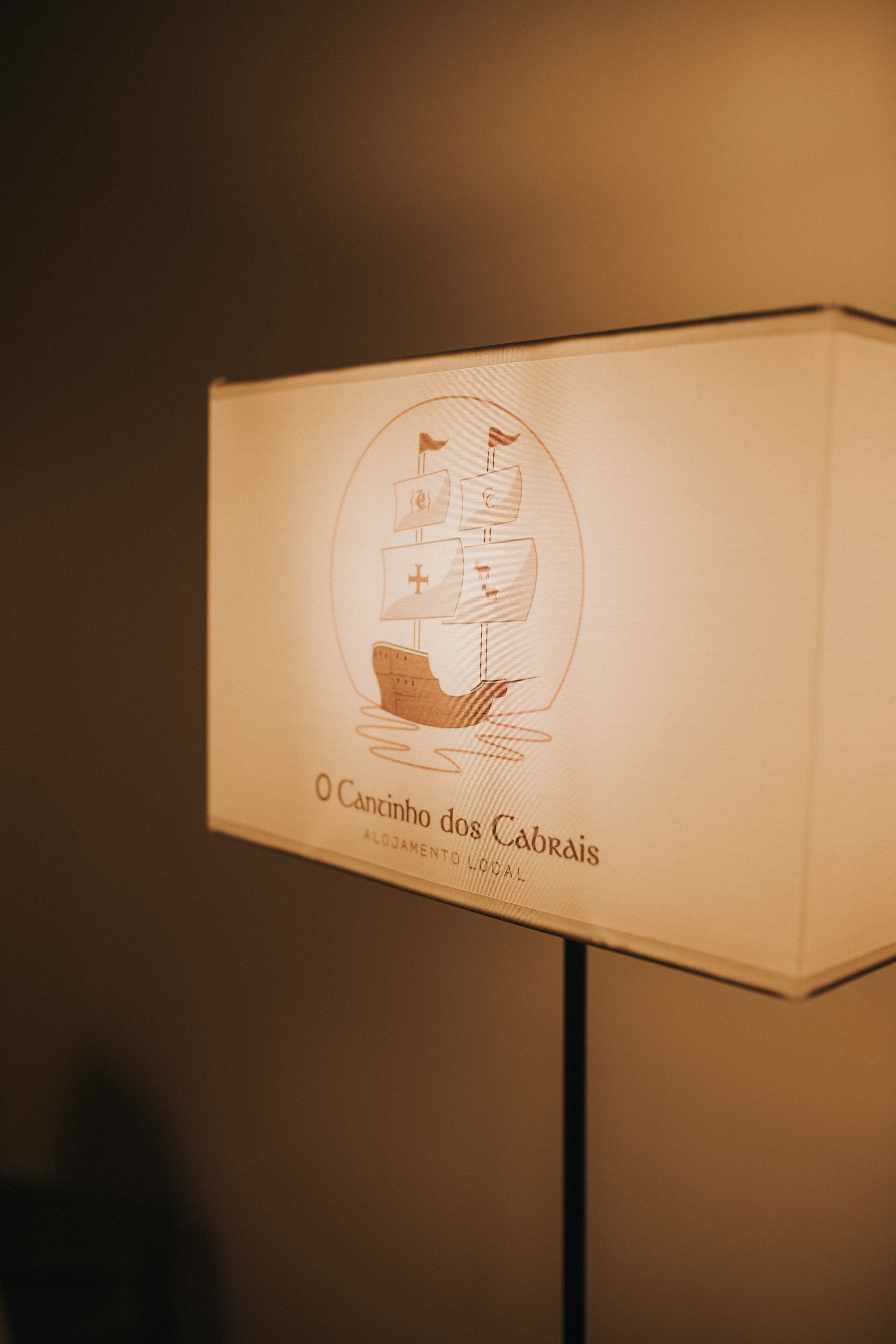 Placa na parede com ilustração de um barco e texto 'O Canhão dos Cabrais Alojamento Local'.