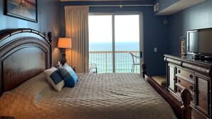 Een slaapkamer met een bed, een plafondventilator, een televisie en uitzicht op de oceaan.