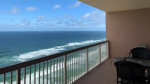 Een balkon met uitzicht op de oceaan, een tafel en twee stoelen.