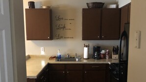 A kitchen with wooden cabinets, a sink, a stove, and a refrigerator. There is a wall-mounted sign with inspirational text. - 228 BEAUTIFUL DOWNTOWN AIR/WIFI/close to FALLS (Buffalo)