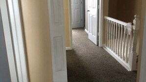 A hallway with carpeted floors, white doors, and a white railing. - 228 BEAUTIFUL DOWNTOWN AIR/WIFI/close to FALLS (Buffalo)