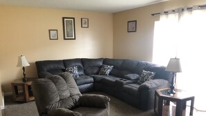 A living room with a sectional sofa, a recliner, two side tables, and framed pictures on the wall. - 228 BEAUTIFUL DOWNTOWN AIR/WIFI/close to FALLS (Buffalo)