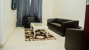 A living room with a sofa, a coffee table, and a television mounted on the wall.