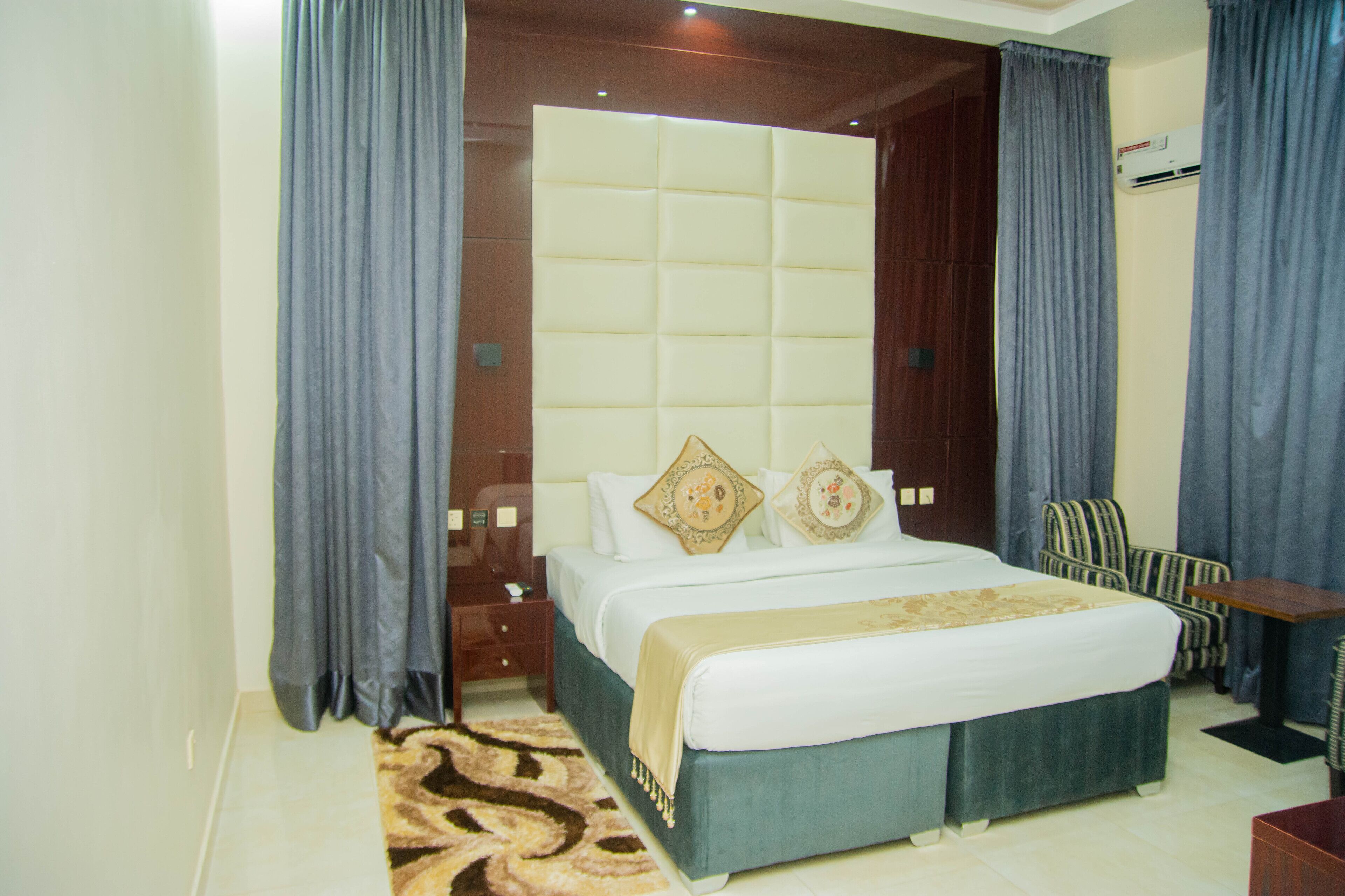 A hotel room with a large bed, a wooden headboard, a desk, and a chair.