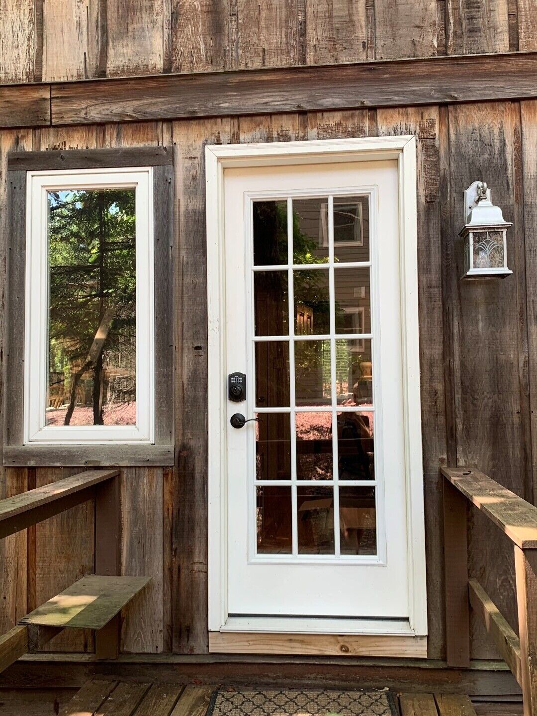 A wooden exterior with a white door and window, a bench, and a lantern.