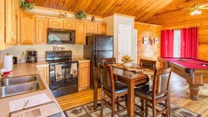 A wooden cabin interior with a kitchen, dining area, and pool table. - GreatView!PoolTable,HotTub,Privacy,Fireplace (Sevierville)