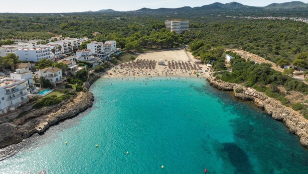 Una vista aerea di una zona costiera con spiaggia, costa rocciosa e edifici.