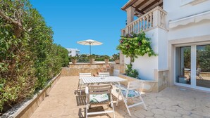 Un patio con tavolo e sedie, una pianta in vaso e vista su un edificio sullo sfondo.