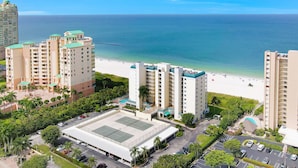 Een strandhotel met meerdere gebouwen, een tennisbaan en een parkeerplaats.