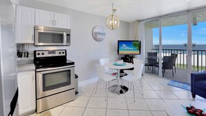 Een moderne keuken met een magnetron, oven en een eethoek met een televisie.