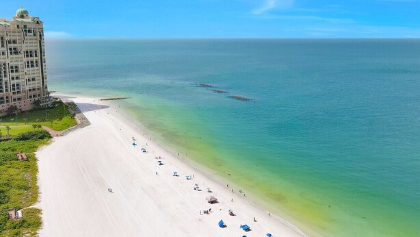 Een strandhotel met een lang zandstrand en helder turquoise water.