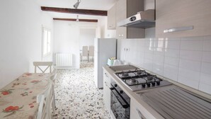 A kitchen with a gas stove, white cabinets, and a terrazzo floor. - Ca' Rosalba, Biennale next to San Marco (Venezia)
