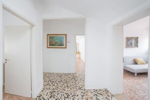 Ein Flur mit einem gemusterten Boden, einem Gemälde an der Wand und einem Sofa mit Kissen.