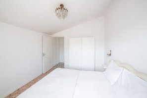 A bedroom with a bed, a chandelier, a wardrobe, and a door.