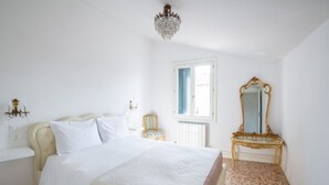 A bedroom with a bed, a chandelier, a mirror, and a window. - Ca' Rosalba, Biennale next to San Marco (Venezia)