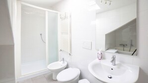 A modern bathroom with a shower, two toilets, a sink, and a mirror. - Ca' Rosalba, Biennale next to San Marco (Venezia)