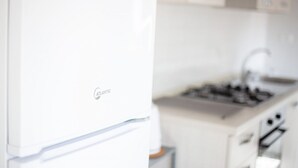 A kitchen with a white refrigerator, a stove, and cabinets.