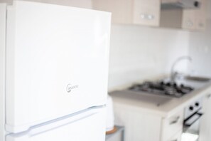 Une cuisine avec un réfrigérateur blanc, une cuisinière et des placards.