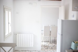 Una cocina con paredes blancas, un radiador blanco y piso de baldosas.
