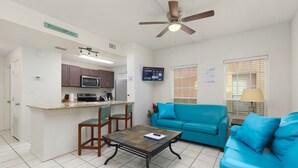 A compact living space with a kitchen, a dining area, and a seating area with a blue sofa and a coffee table. - Sun Ray #1B - Pet Friendly, 3min Walk to Beach (South Padre Island)