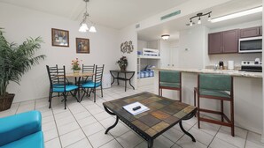 A compact kitchen with a dining area, a small table, and a bar counter. - Sun Ray #1B - Pet Friendly, 3min Walk to Beach (South Padre Island)