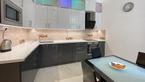 Cocina moderna con microondas, estufa y lavabo. Hay una mesa de comedor con un plato de comida.
