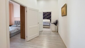 Un pasillo que conduce a un dormitorio con una cama, una puerta y un cuadro en la pared.