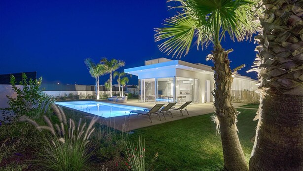 Una casa moderna con piscina, area relax esterna e palme.