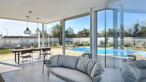 Un'area esterna moderna con piscina, ampie finestre e zona pranzo.