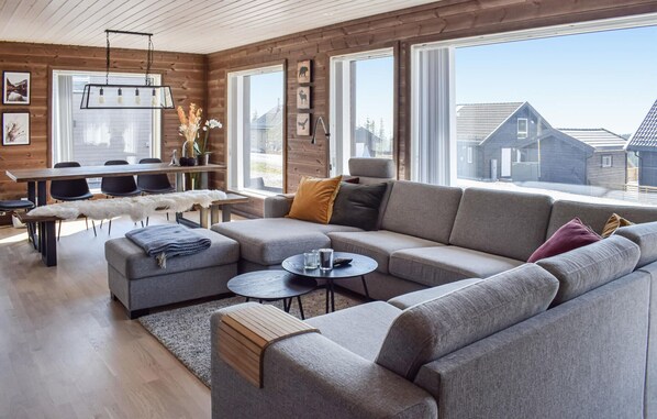 Relax in this stylish living room with a large sofa, coffee table, and dining area offering a view of the surrounding area.