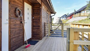 A wooden cabin with a door, a broom, and a wooden deck leading to a rocky area. - 4 bedroom cozy home in Sjusjøen (Sjusjøen)