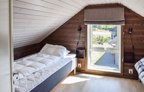Cozy attic bedroom with a single bed, bedside table, and window offering a view of the outside.
