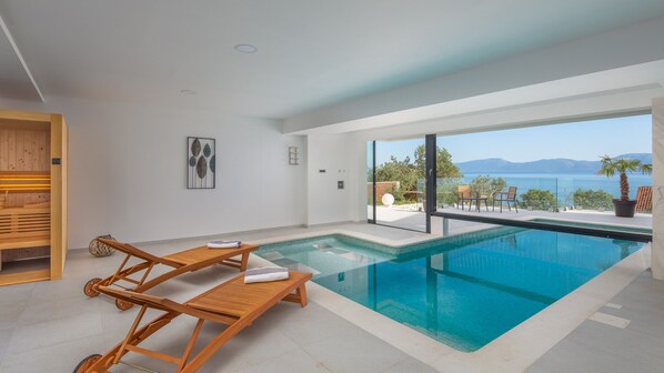 Una piscina interior moderna con vistas despejadas al mar y a las montañas.