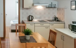 Une cuisine compacte comprenant une table à manger, des chaises, une bouilloire, un grille-pain et un four à micro-ondes.