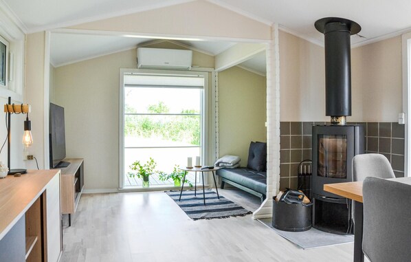 A modern living room with a fireplace, a sofa, a TV, and a dining area.