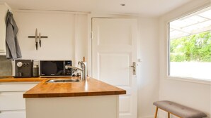 A compact kitchen with a wooden countertop, a microwave, a coffee maker, and a sink. - 2 bedroom amazing home in Kirke Såby (Kirke Såby)