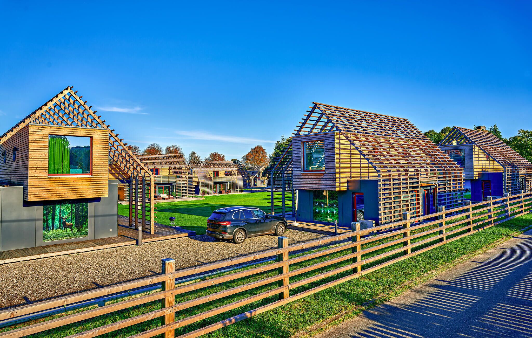 Een rij houten huizen met een grindpad en een houten omheining.