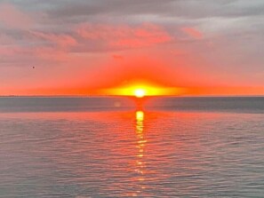 Un coucher de soleil sur une mer calme, avec un horizon dégagé.