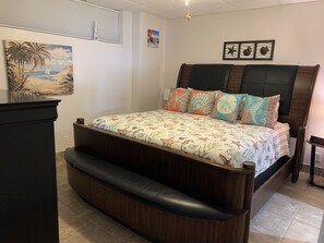 Une chambre à coucher avec un lit, une table de chevet, un bureau et un tableau accroché au mur.