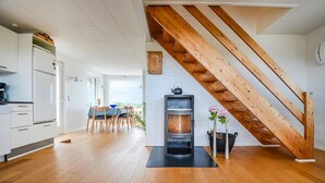 Une cuisine moderne avec un escalier en bois, un poêle à bois encastré et un coin repas offrant une vue agréable.