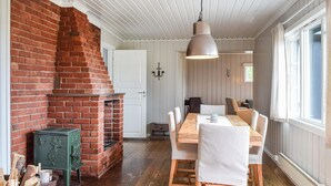 Un rincón comedor acogedor con chimenea de ladrillo, mesa de madera y sillas.