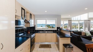 A modern kitchen with a view of the landscape, a dining area with a sofa, and a small table. - Torino 7 - 7/14 Nettin Circuit (Jindabyne)