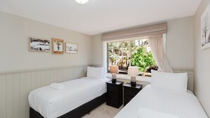 A double room with two beds, a window with curtains, a bedside table with a lamp, and wall art. - Torino 7 - 7/14 Nettin Circuit (Jindabyne)