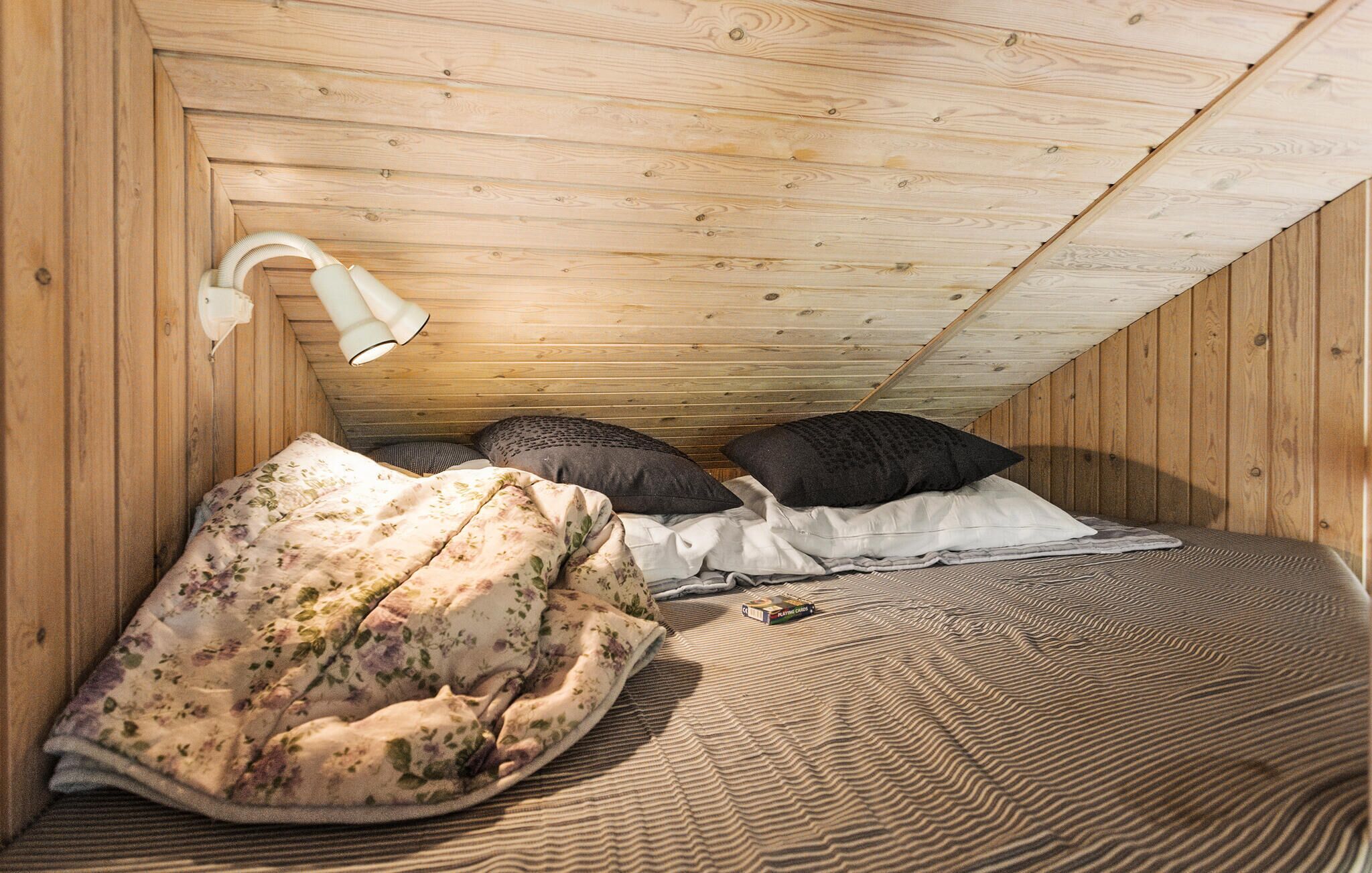 A cozy attic bedroom with wooden walls and a sloped ceiling.