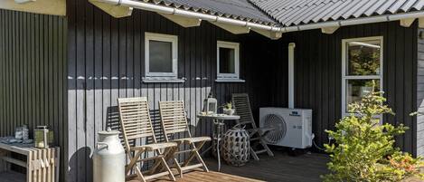A wooden deck with outdoor furniture, a table, and a portable heater.