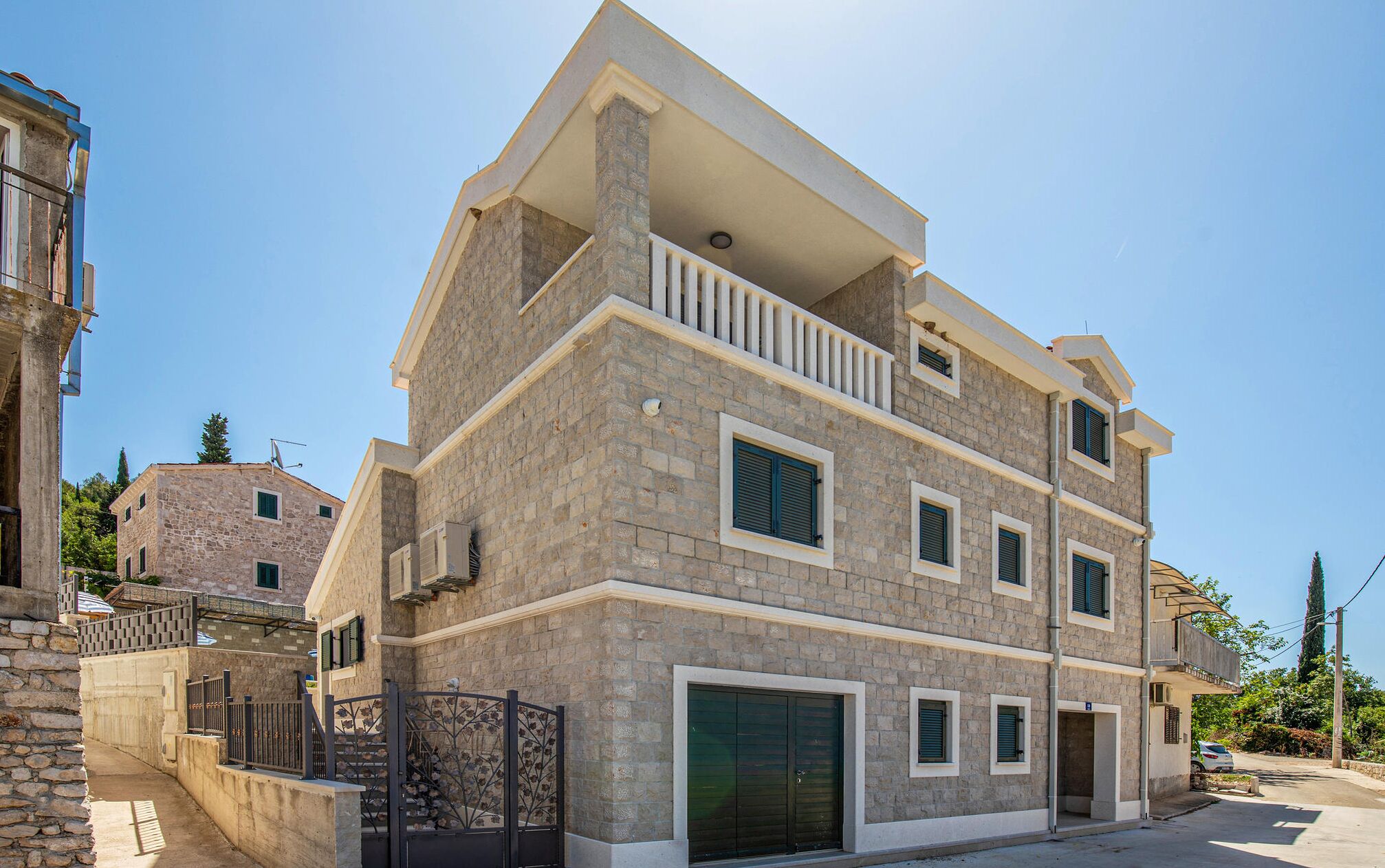 A multi-story building with a stone facade, a balcony on the upper floor, and a gated entrance.