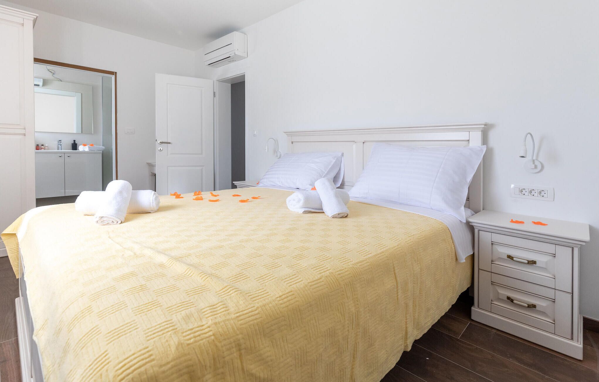 Ein Hotelzimmer mit Bett, Nachttisch, Spiegel, Kleiderschrank und Klimaanlage.
